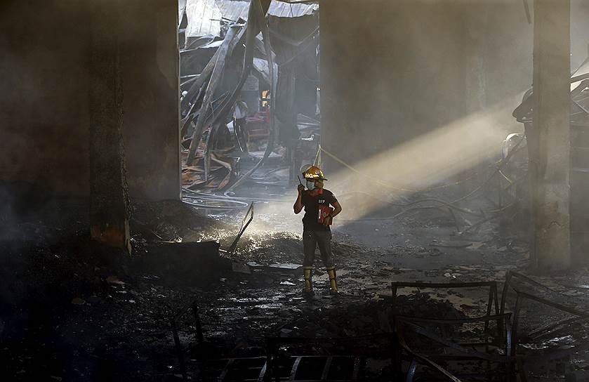 Манила, Филиппины. Пожарный следователь во время работы на сгоревшей фабрике по производству резиновых тапочек, во время пожара на которой погибли более 30 человек