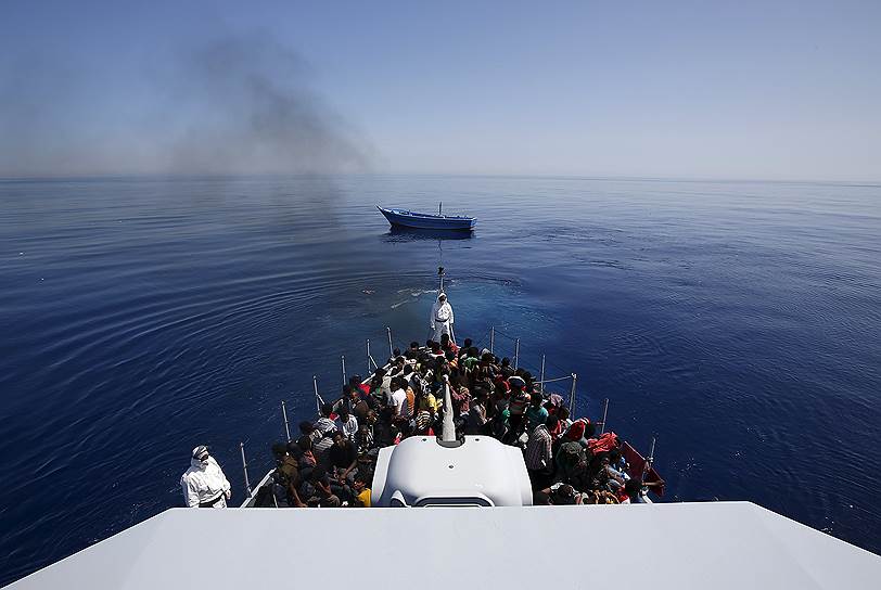 Средиземное море, Италия. Три сотни мигрантов из Африки были спасены с их лодки (на заднем плане) недалеко от берегов Лампедузы