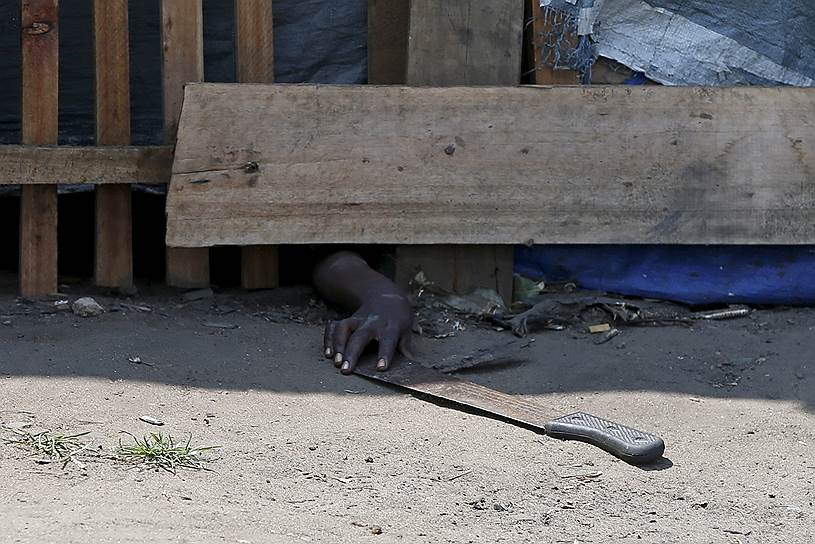 Бужумбура, Бурунди. Протестующий, прячущийся от полиции, тянется к мачете