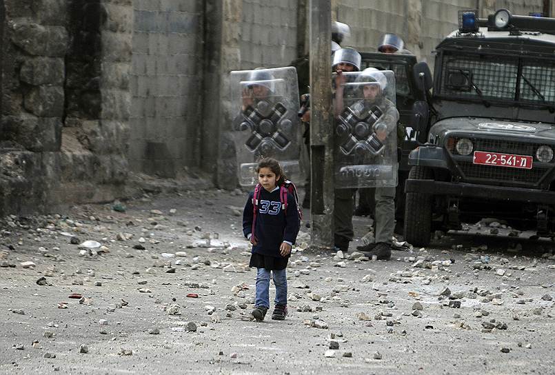 Палестинская девочка переходит израильскую границу по пути из школы во время столкновений палестинцев с израильской армией