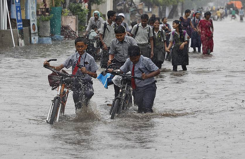 Школьники индийского города Ахмедабад идут из школы во время начавшегося сезона дождей 
