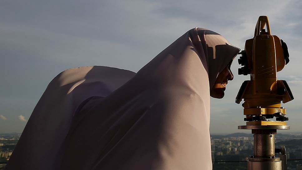 Куала-Лумпур, Малайзия. Женщина-мусульманка смотрит через теодолит на новолуние, которое сигнализирует о начале священного месяца Рамадан