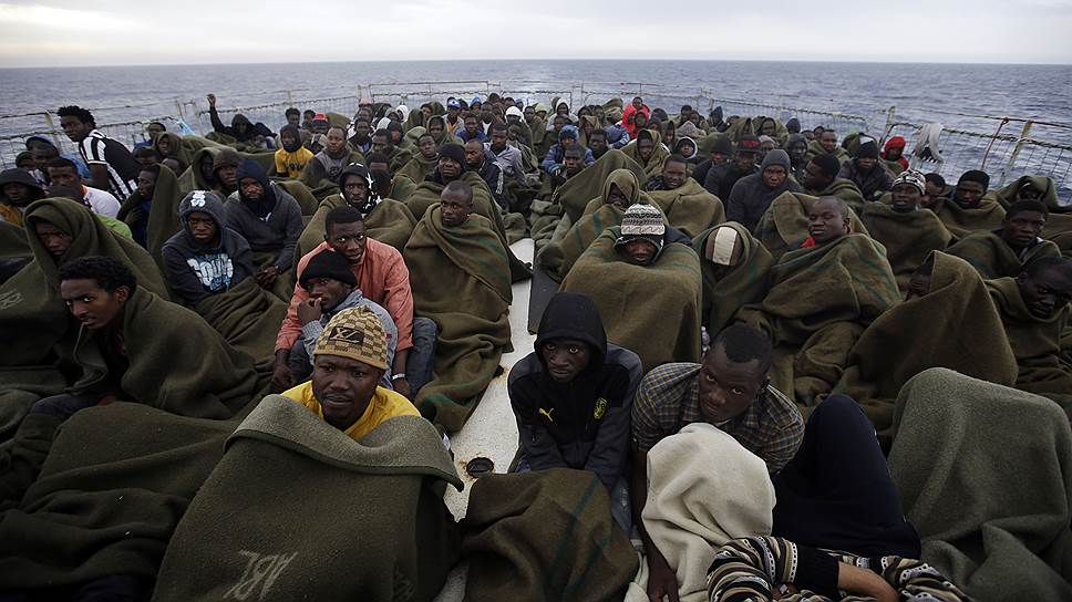 Мигранты сидят на палубе корабля после спасательной операции в Средиземном море