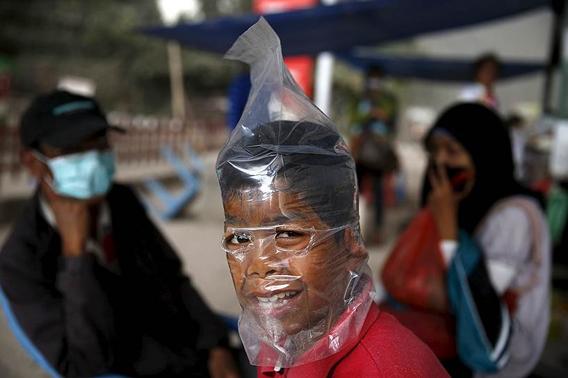 Брастаги, Индонезия. Мальчик с пакетом на голове, надетым для защиты от пепла, извергаемого вулканом Синабунг