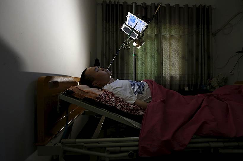 Цюйчжоу, Китай. 32-летний Сюй Яньхуа, потерявший способность двигаться из-за сильной травмы спины, управляет своим интернет-магазином по продаже носков с помощью удлиненного стилуса и планшетов, установленных над кроватью