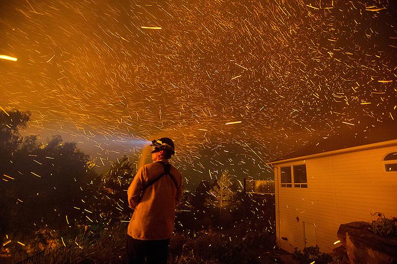 Уэнатчи, США. Спасатель защищается от горящих углей. Пожары в штате Вашингтон, вызванные сильным ветрам и повышенными температурами, уничтожили не менеее 20 домов