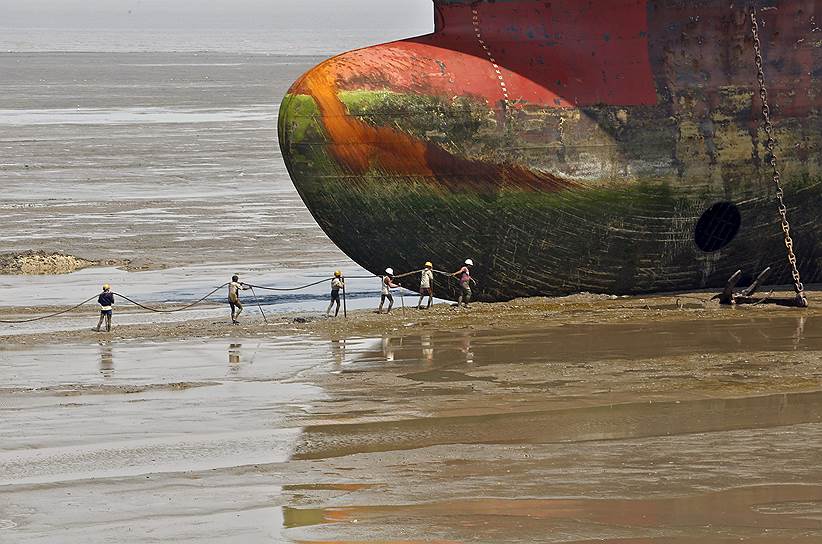 Аланг, Индия. Рабочие несут веревку для крепления списанного судна на судоверфь
