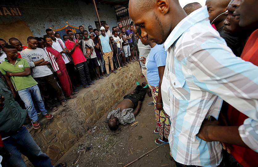 Бужумбура, Бурунди. Прохожие возле тела убитого во время столкновений в день президентских выборов 