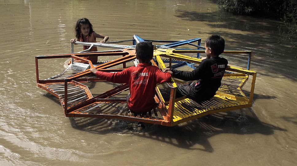 Лахор, Пакистан. Дети, катающиеся на карусели во время наводнения, вызванного проливными дождями