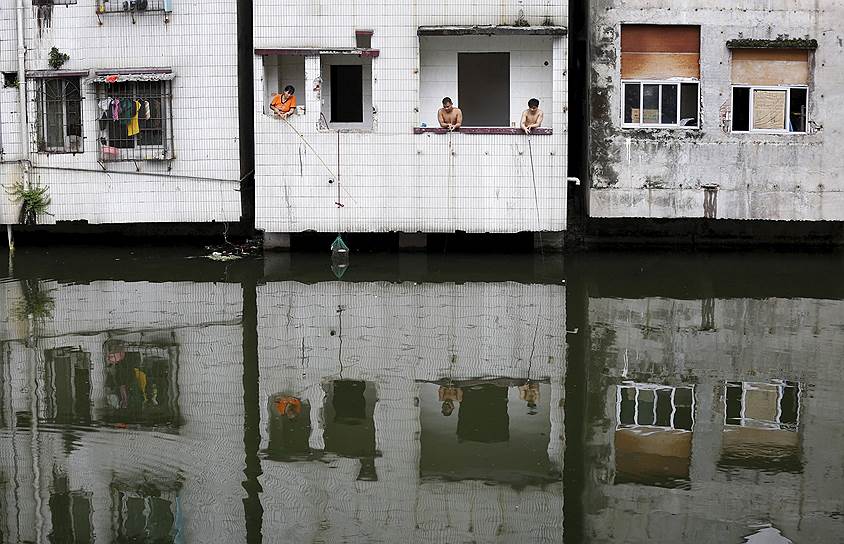 Гуанчжоу, Китай. Люди рыбачат из окон заброшенного дома в трущобном районе города