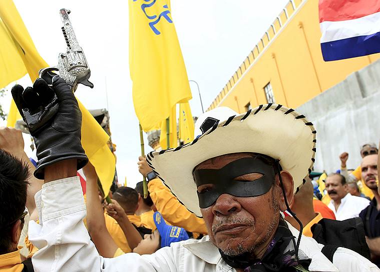 Сан-Хосе, Коста-Рика. Демонстрант в маске и с игрушечным пистолетом во время акции протеста госслужащих против «налоговой несправедливости» и маленьких зарплат