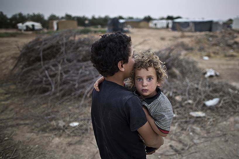 Мафрак, Иордания. Сирийский беженец несет на руках младшего брата