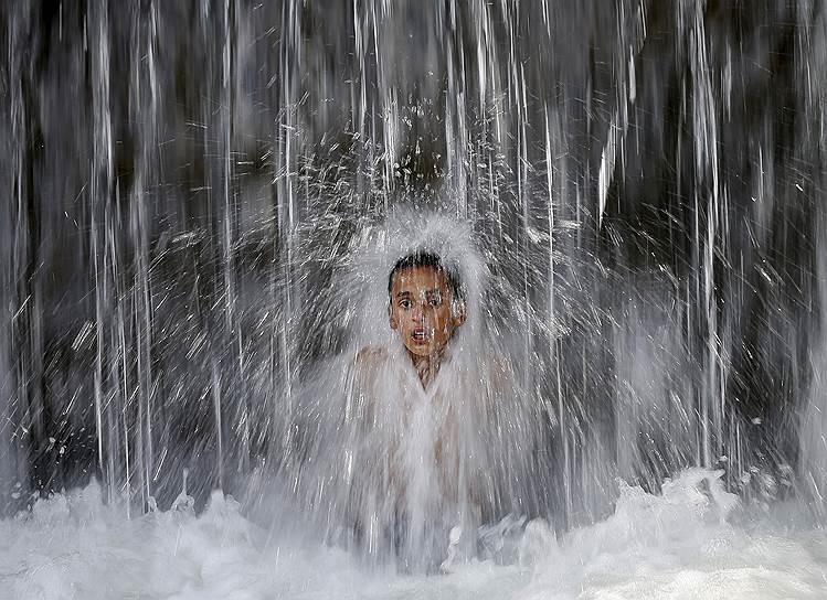 Кабул, Афганистан. Мальчик, играющий в водопаде в жаркий день