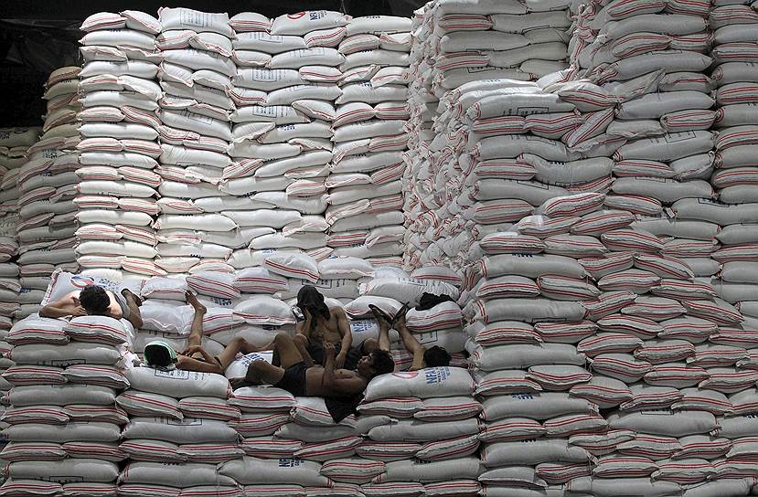 Манила, Филиппины. Рабочие на мешках с рисом на государственном складе продуктов питания