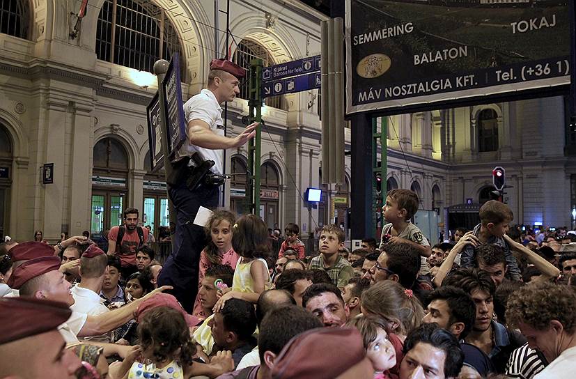 Будапешт, Венгрия. Полицейский в толпе мигрантов, штурмующих поезда, следующие в Германию и Австрию