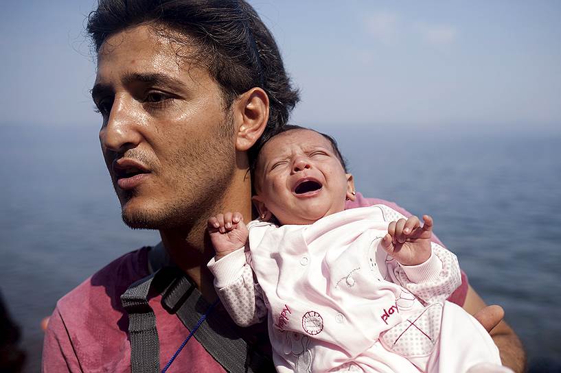 Сирийский беженец из Алеппо со своей месячной дочерью после прибытия на греческий остров Лесбос