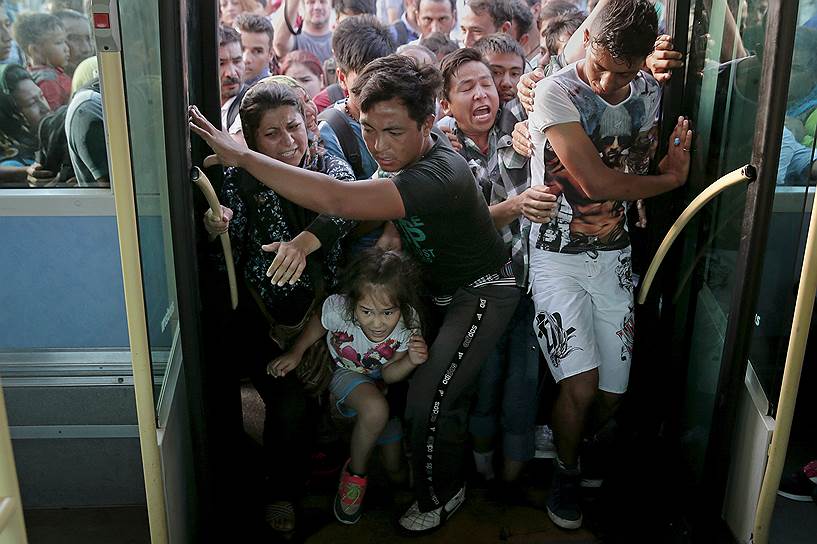 Сирийские беженцы пытаются сесть на автобус по прибытии в порт Пирей близ Афин на борту пассажирского судна  «Eleftherios Venizelos»
