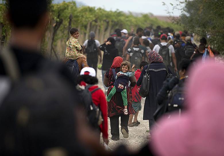 Мигранты идут по грунтовой дороге после пересечения греко-македонской границы в районе города Гевгелия