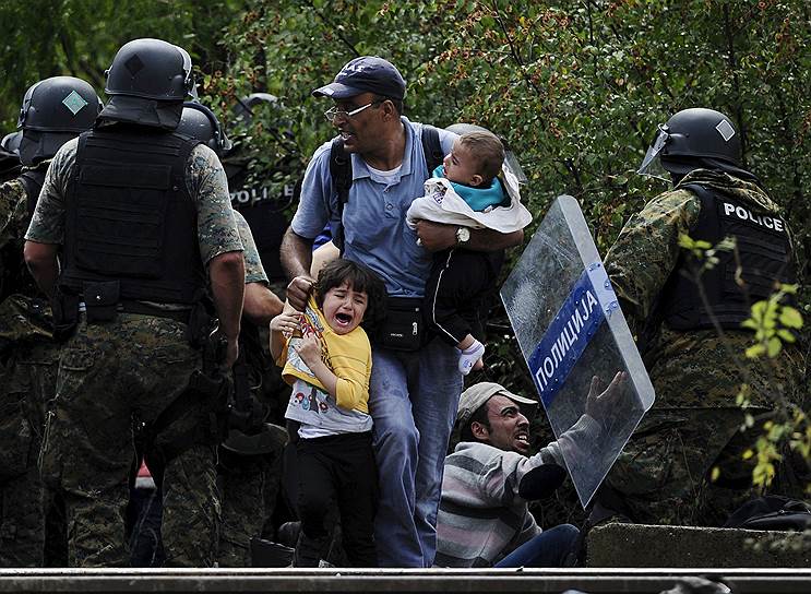 Мужчина с детьми на руках после пересечения греко-македонской границы, где на прошлой неделе мигранты пытались прорваться на территорию Македонии