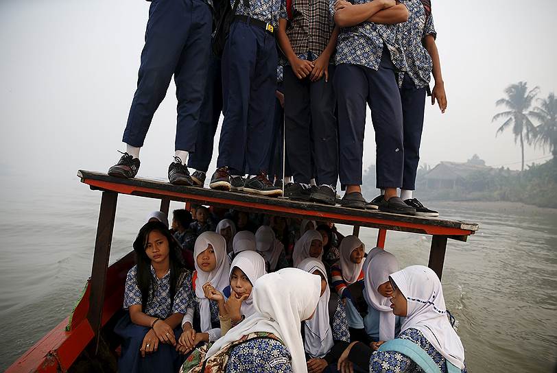 Палембанг, Индонезия. Дети, плывущие на деревянной лодке в школу