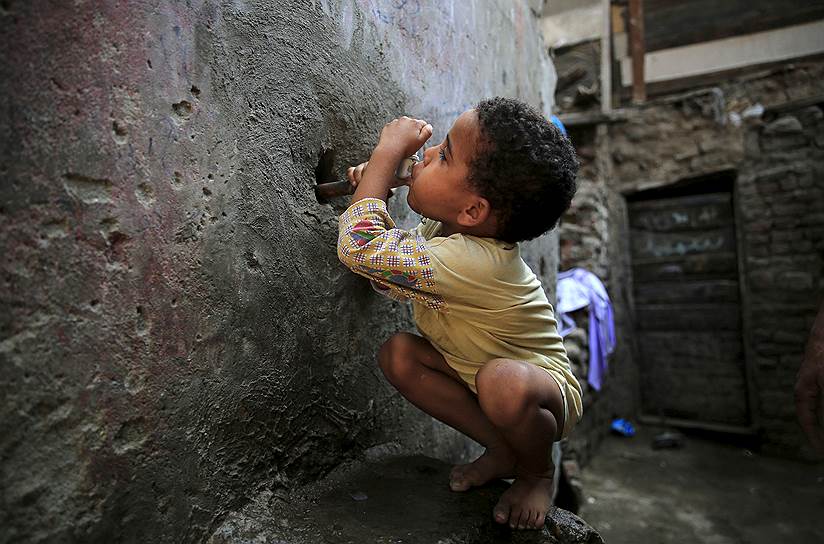 Гиза, Египет. Пятилетний мальчик пытается попить воды из водопроводного крана в стене дома в трущобном районе Эшаш-эль-Судан