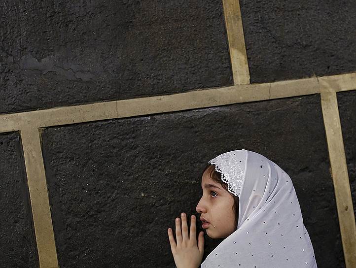 Мекка, Саудовская Аравия. Девочка касается Каабы, мусульманской святыни в Заповедной мечети
