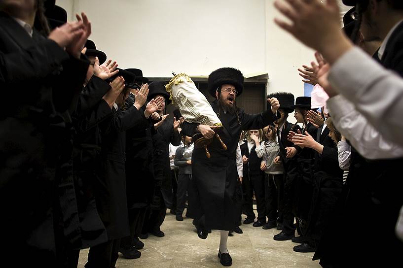 Иерусалим, Израиль. Ортодоксальный еврей танцует со свитком Торы во время празднования Симхат Тора