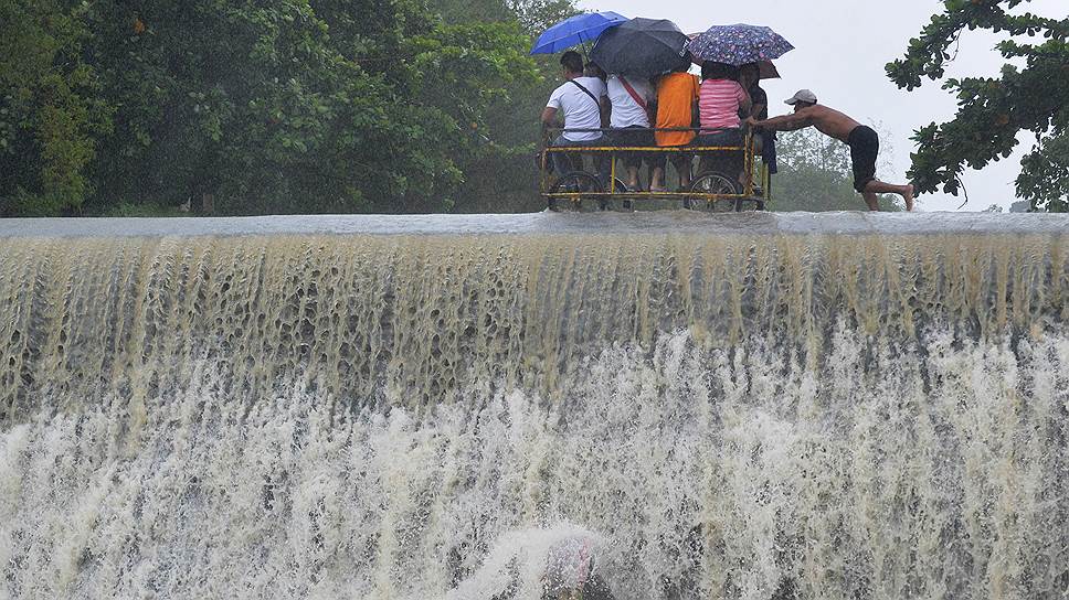 Манила, Филиппины. Местные жители, пересекающие плотину во время наводнения, вызванного тайфуном Коппу