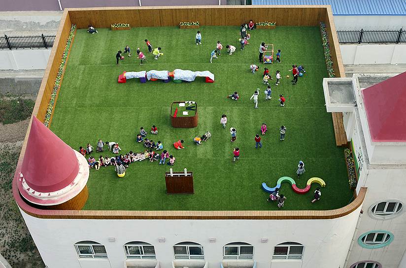 Сиань, Китай. Дети и воспитатели на игровой площадке детского сада, расположенной на крыше 