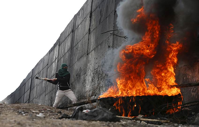 Абу-Дис, Палестина. Палестинский демонстрант пытается проделать дыру в стене, отделяющей палестинское селение от израильского Иерусалима