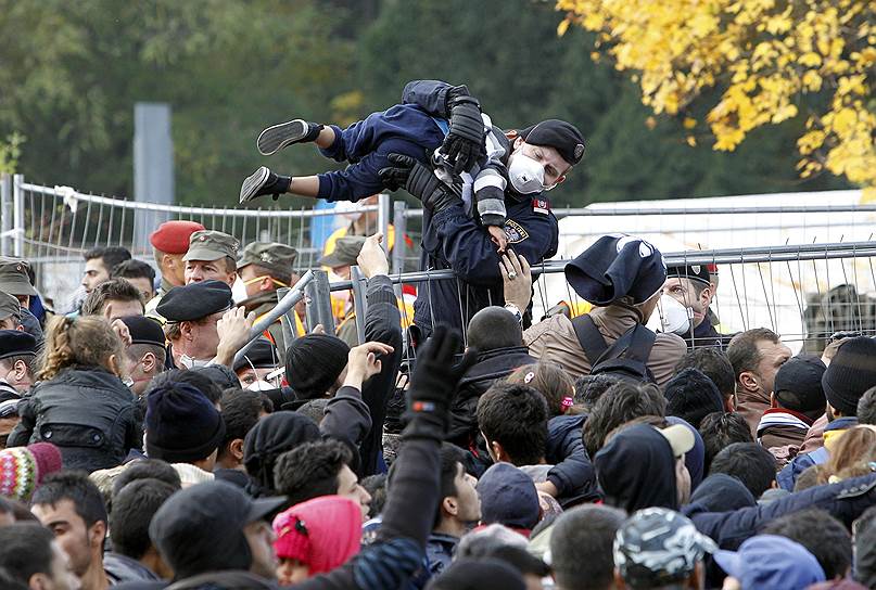 Сентиль, Словения. Австрийский полицейский вынимает мальчика из толпы мигрантов, ожидающих разрешения на пересечение границы с Австрией