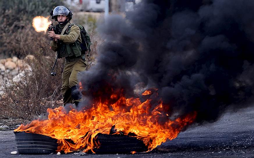 Рамаллах, Палестина. Израильский солдат стреляет про протестующим палестинцам во время столкновений у еврейского поселения Бет-Эль