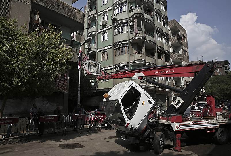 Каир. Рабочий поднимается на кране, чтобы прикрепить флаг Египта на фонарный столб, находящийся рядом с моргом, в котором находятся тела жертв крушения самолета «Когалымавиа»