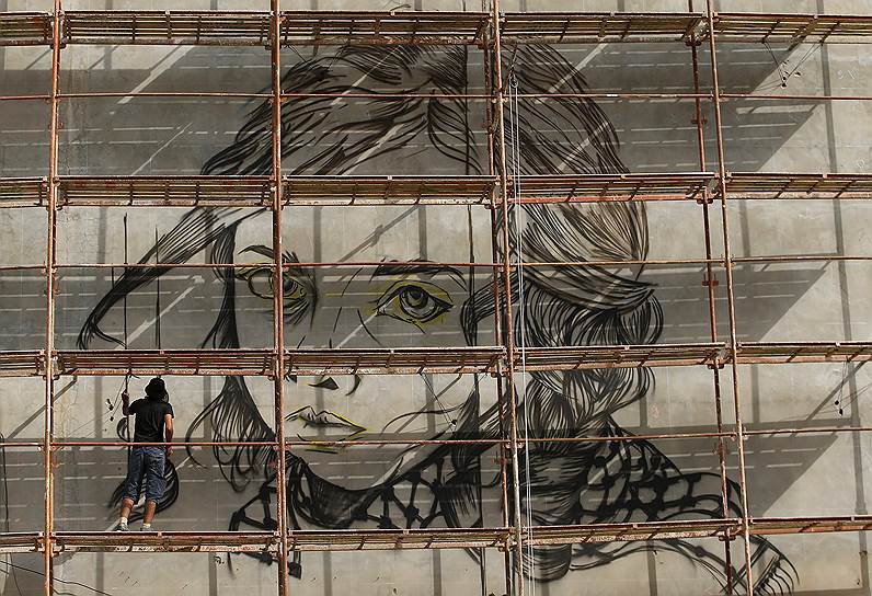 Газа, Палестина. Художник Белал Халед во время работы над изображением палестинской девочки на стене башни