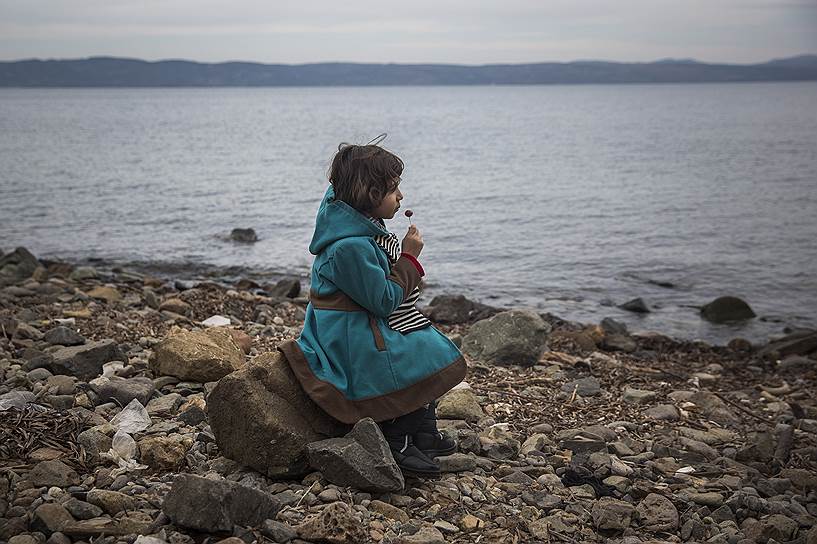 Лесбос, Греция. Девочка из Сирии сидит на берегу после прибытия с семьей на лодке из Турции