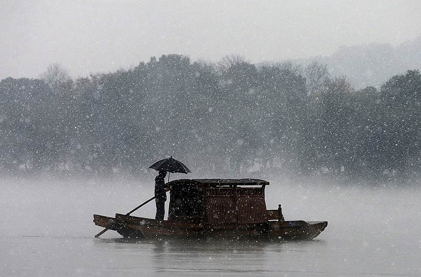 Ханчжоу, Китай. Лодочник на Западном озере во время снегопада