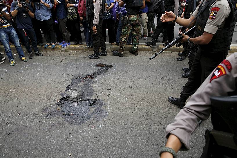 Полицейские с оружием стоят возле пятна крови в деловом районе в индонезийской столице Джакарте, где прогремели шесть взрывов, а затем завязалась перестрелка. По предварительным данным, погибли 17 человек, 4 из которых были нападавшими. Ответственность за происшедшее взяла на себя террористическая организация «Исламское государство» 