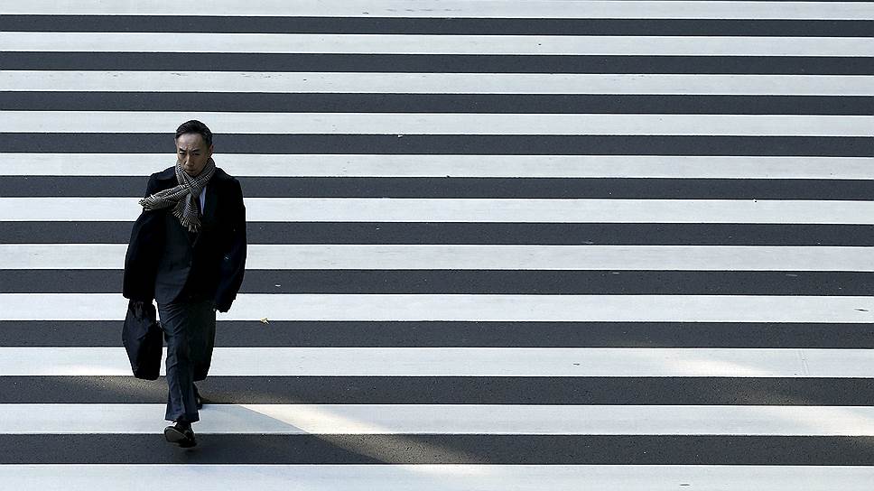 Токио, Япония. Бизнесмен пересекает дорогу в деловом районе 