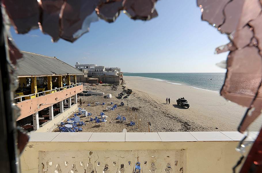 Могадишо, Сомали. Вид через разбитое стекло на правительственные войска, которые патрулируют пляж после нападения на пляжный ресторан