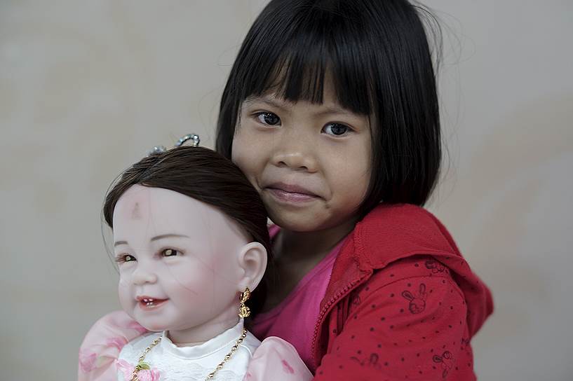 На фото: 6-летняя девочка держит на руках «детского ангела» в одном из универмагов в Бангкоке