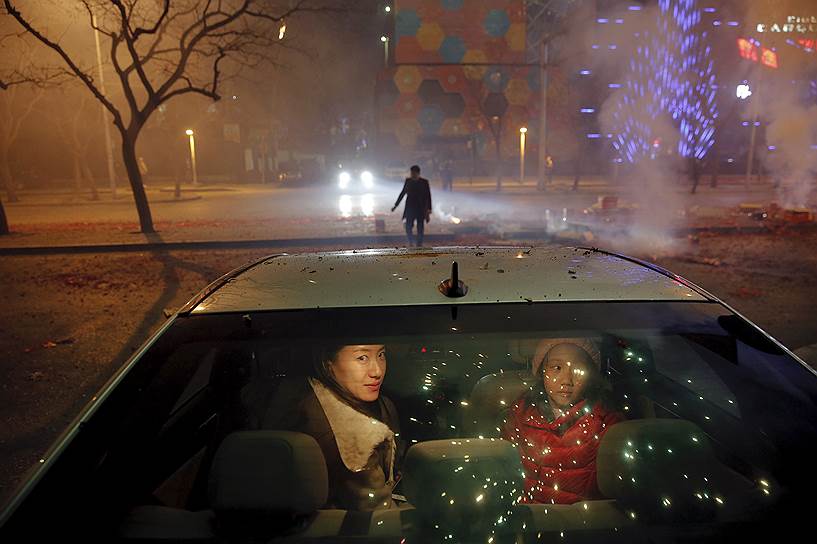 Пекин, Китай. Местные жители смотрят на фейерверки в честь Лунного нового года