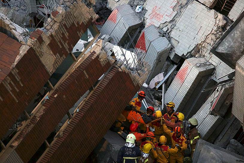 Тайнань, Тайвань. Спасатели несут выжившего под завалами 17-этажного дома, рухнувшего при землетрясении 