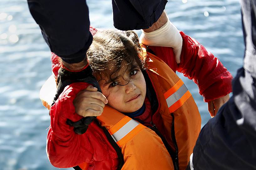 Лесбос, Греция. Сотрудник береговой охраны вытаскивает девочку из лодки с мигрантами во время спасательной операции
