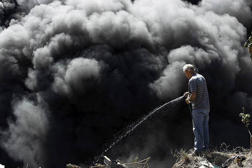Сан-Хосе, Коста-Рика. Мужчина, пытающийся потушить пожар на нелегальной свалке, подожженной местными жителями, чтобы остановить распространение вируса Зика