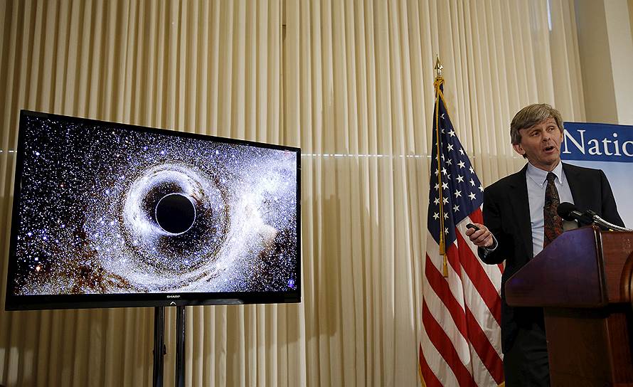 Доктор Дэвид Ритц, исполнительный директор LIGO в Калифорнийском технологическом институте, показывает слияние двух черных дыр во время пресс-конференции, на которой было объявлено об обнаружении гравитационных волн