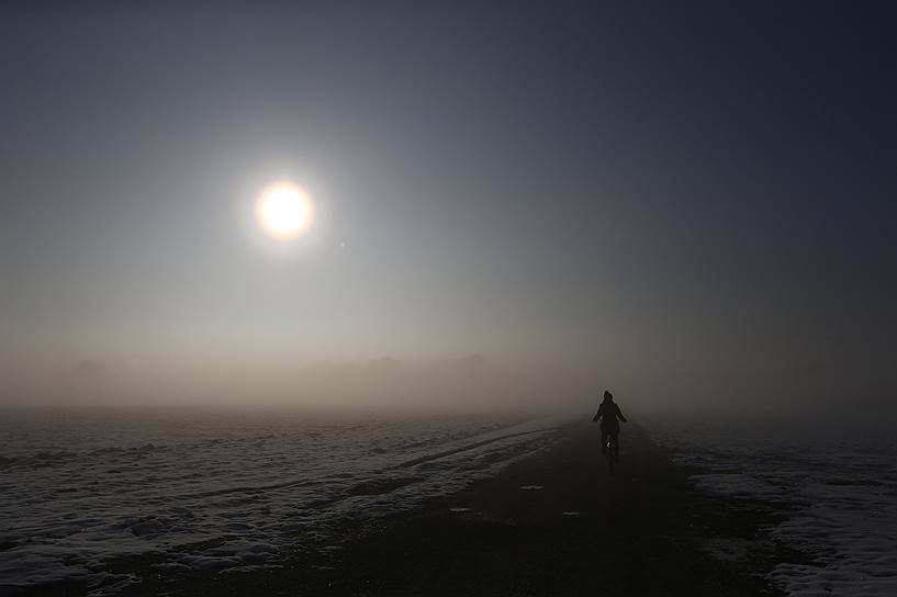Ольхинг, Германия. Велосипедист едет по дороге ранним утром