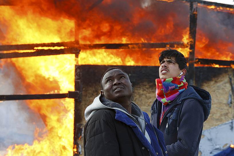 Кале, Франция. Мигранты у горящего жилища во время ликвидации стихийного поселения беженцев, называемого «Джунглями»