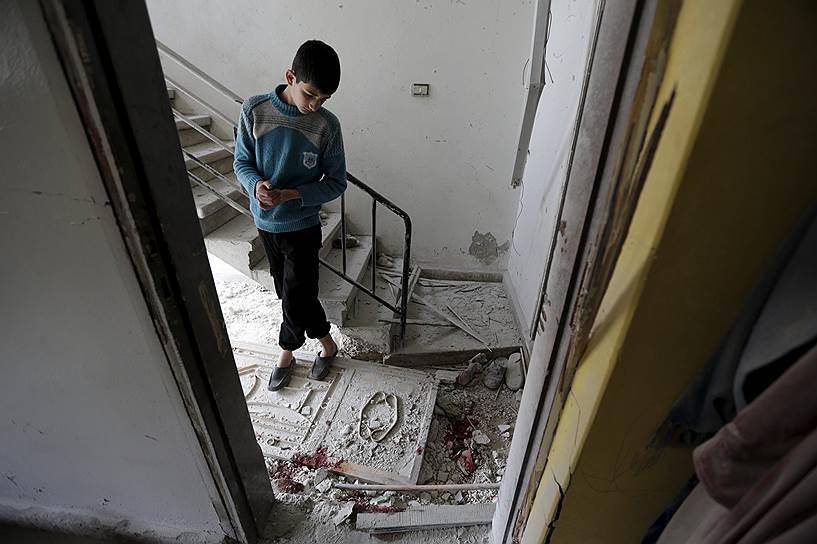 Хан-Шейхун, Сирия. Мальчик осматривает последствия обстрела города, контролируемого повстанцами