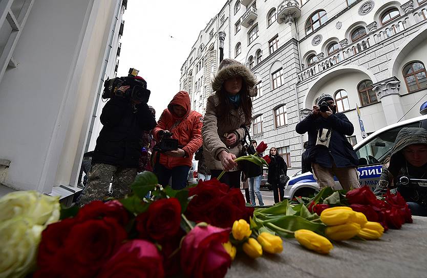 Люди несут цветы к посольству Бельгии в Москве