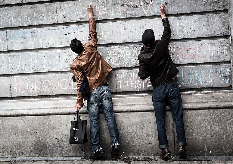 Брюссель, Бельгия. Двое мужчин пишут на стене мемориала жертвам террористических атак в Брюсселе